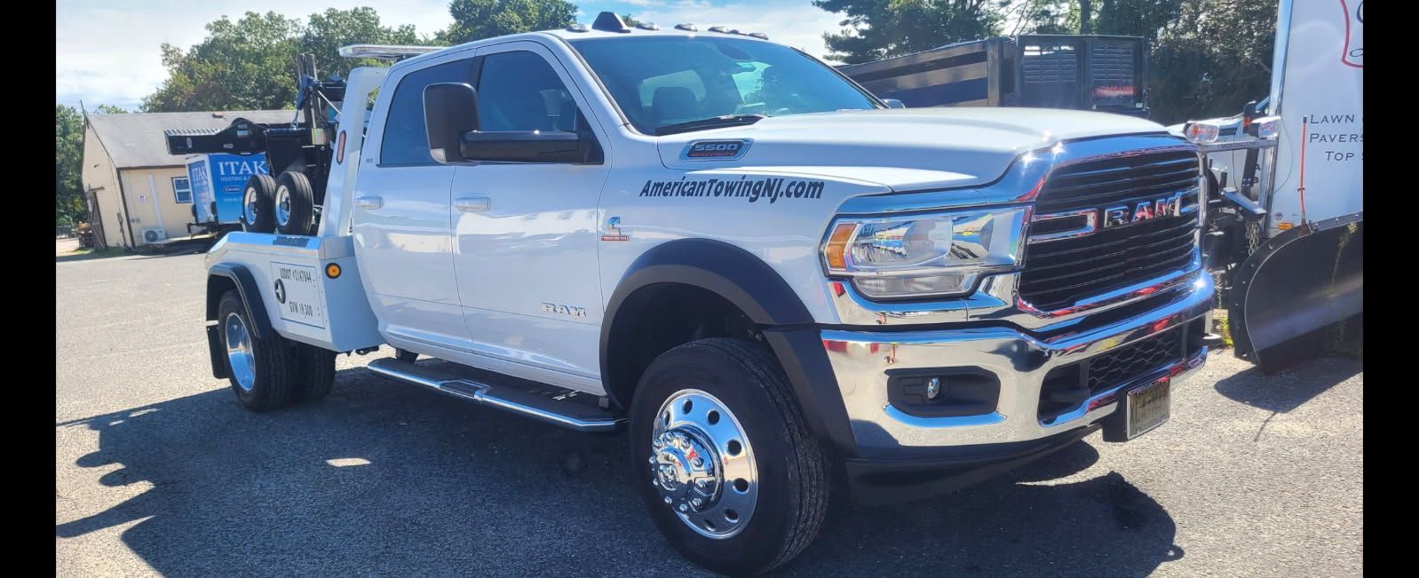 White tow truck parked on asphalt. Ram logo on the front grill.