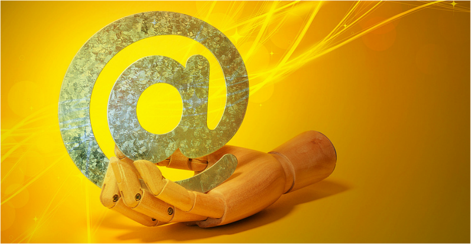 Wooden hand holding an @ symbol referencing email marketing