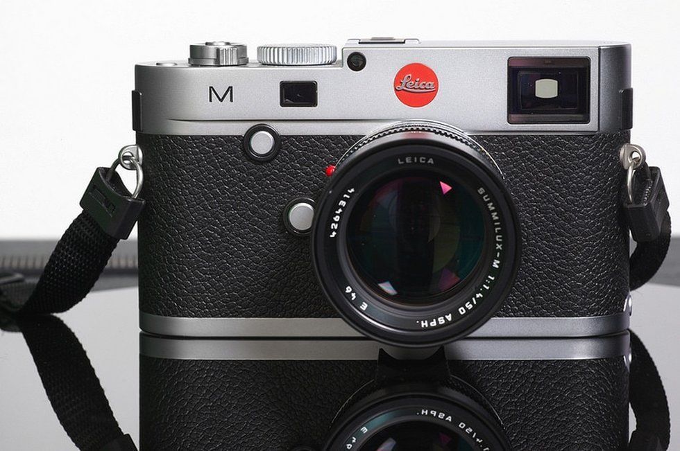 A silver leica camera with a black strap