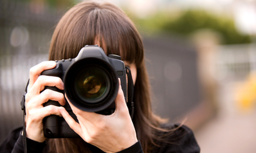 Woman with a camera looking down the lens