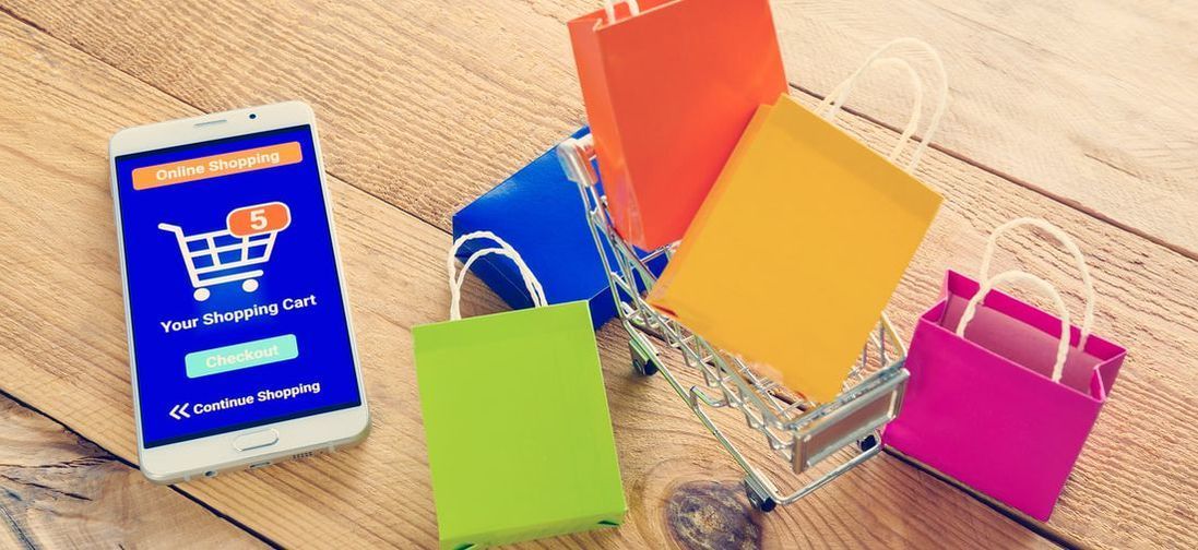 Shopping cart on mobile phone next to minature shopping cart