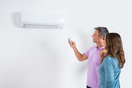 A man and a woman are looking at an air conditioner.