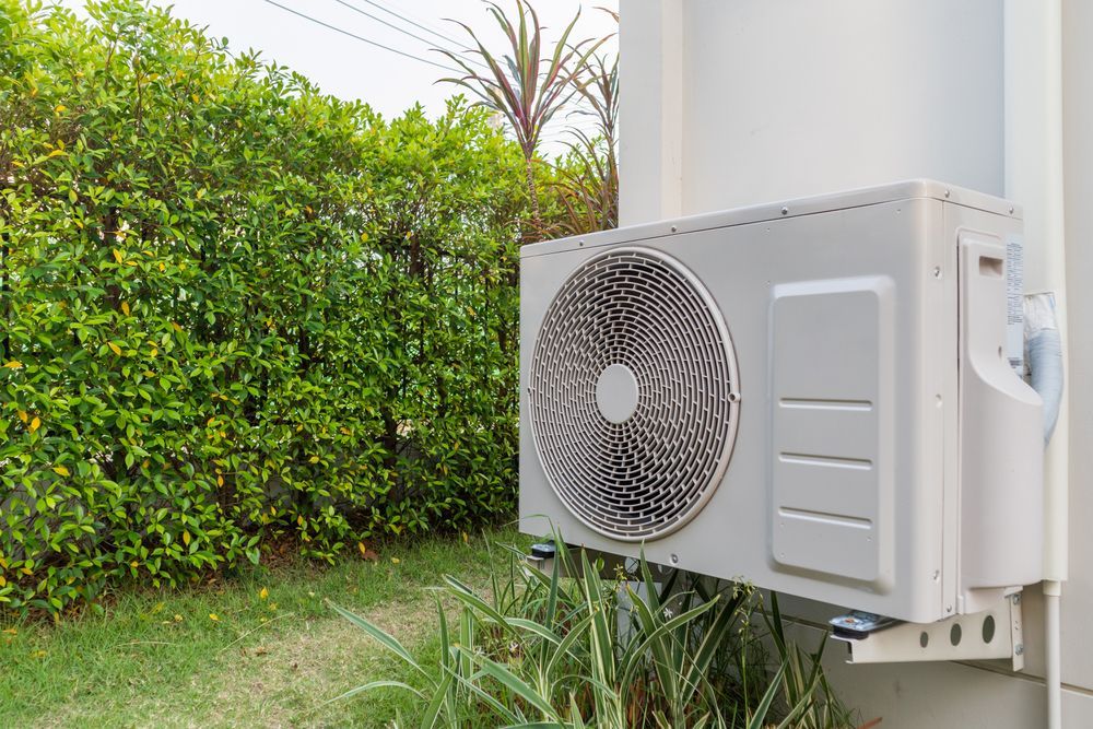 A white air conditioner is mounted on the side of a building.