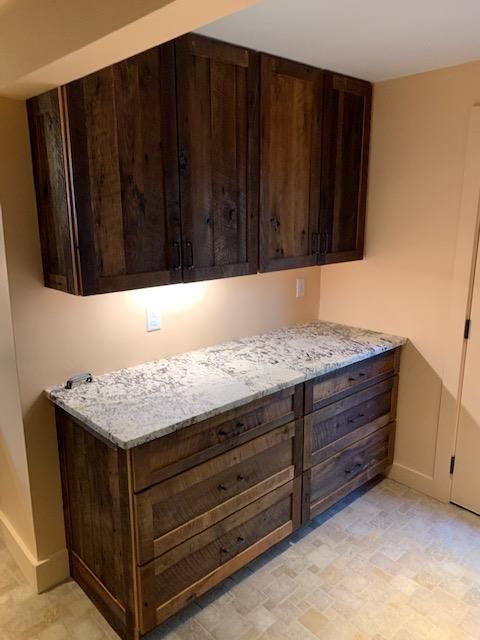 Rustic wood cabinets with a light granite countertop in a small room with tan walls.