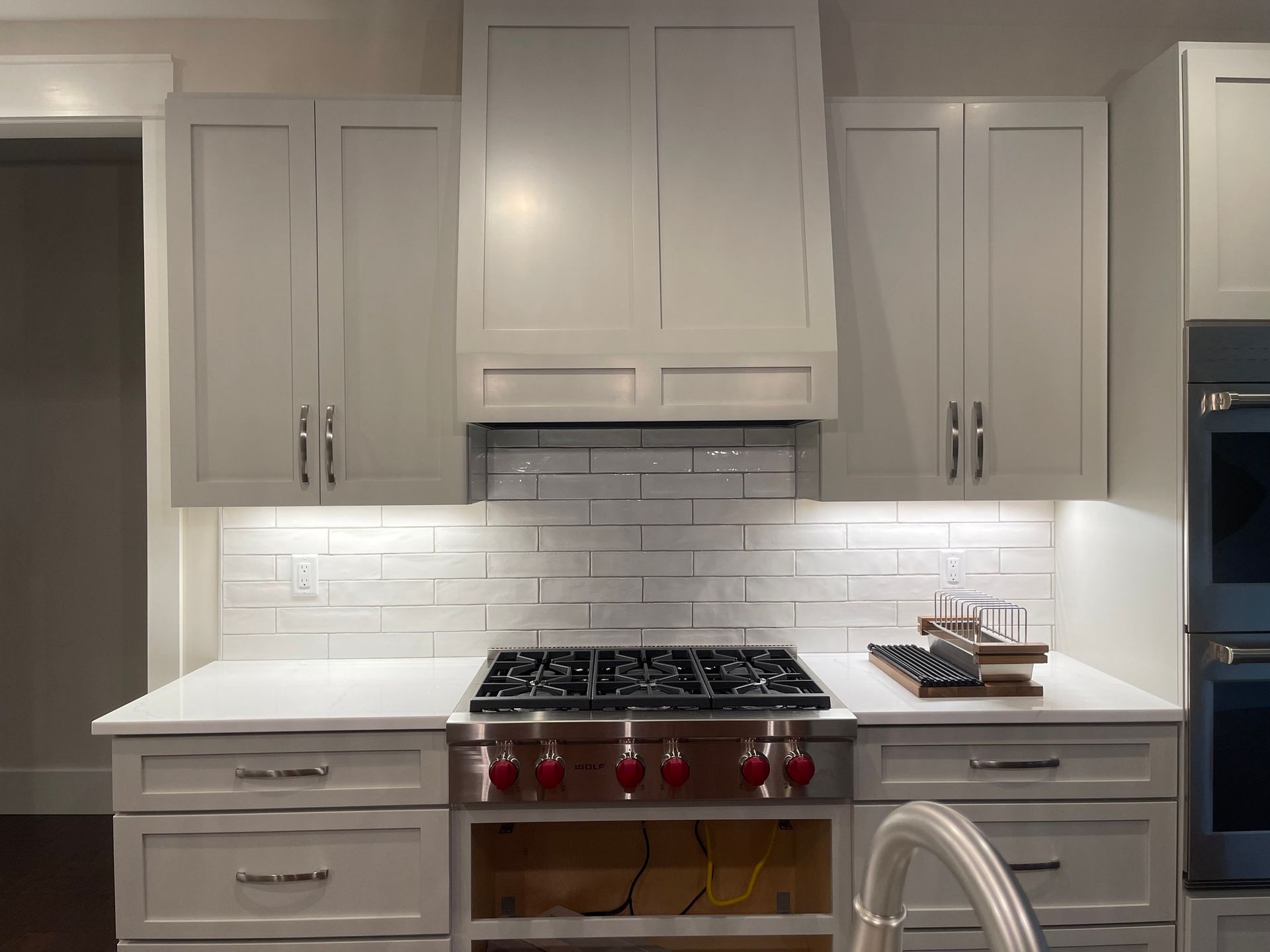 A kitchen view featuring light gray shaker cabinets, a white subway tile backsplash, and a stainless steel gas range.