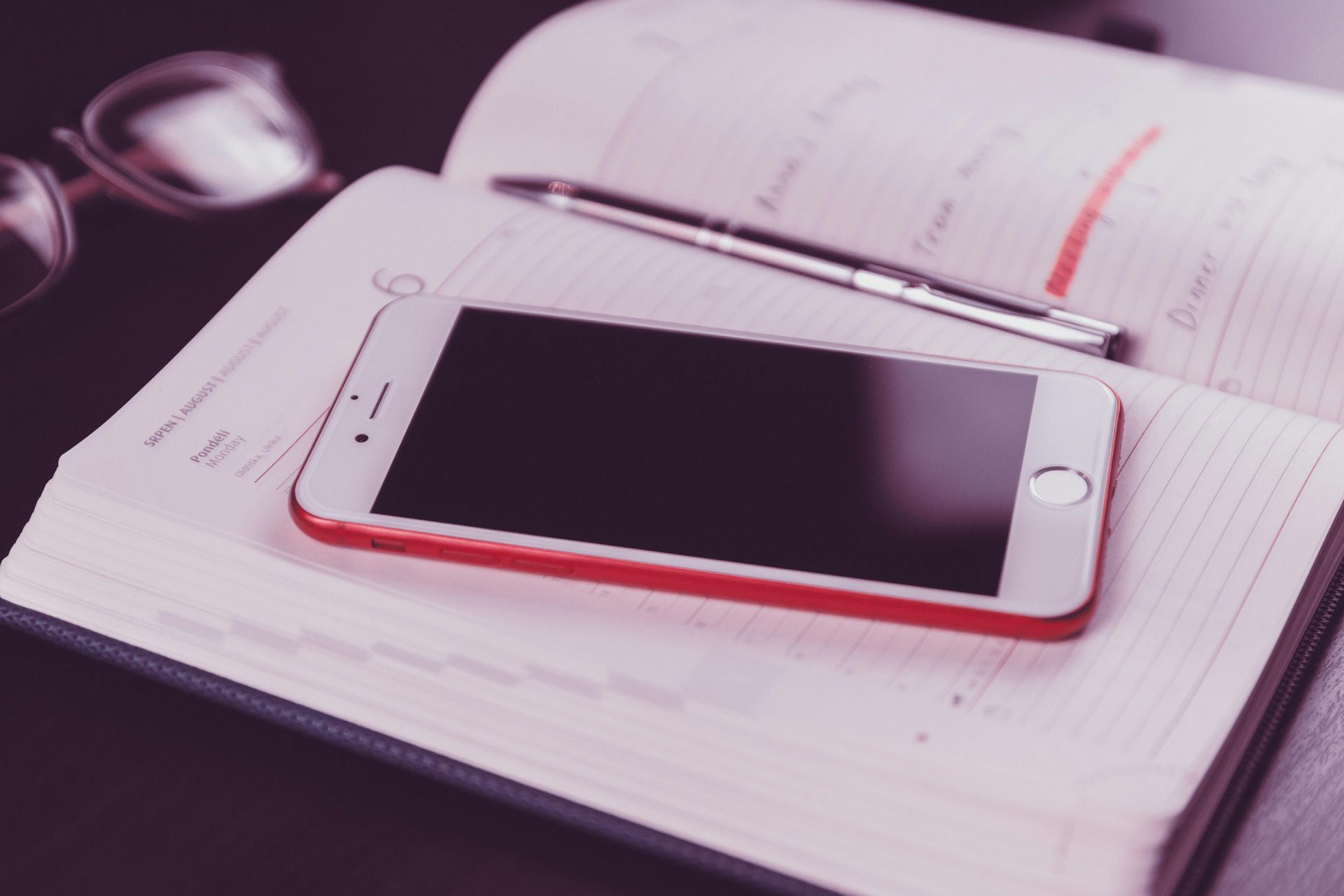 A cell phone is lying on top of a day planner