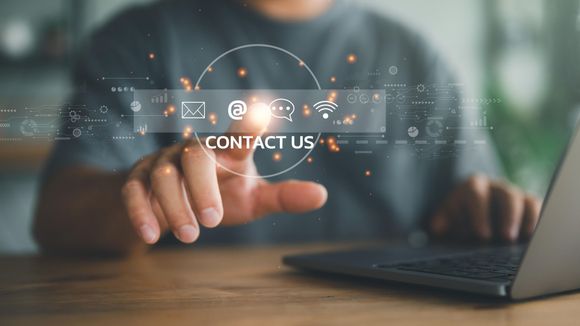 a man is using a laptop computer and pressing a button that says `` contact us '' .