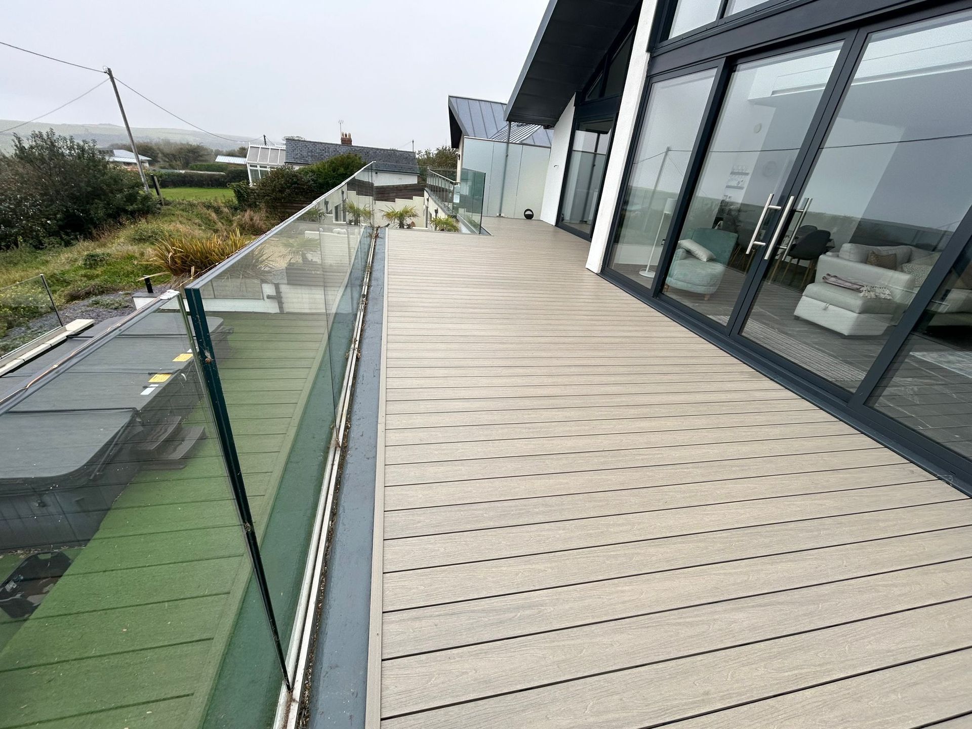 Composite decking installation with glass balustrade by C4W in Tenby, Pembrokeshire.