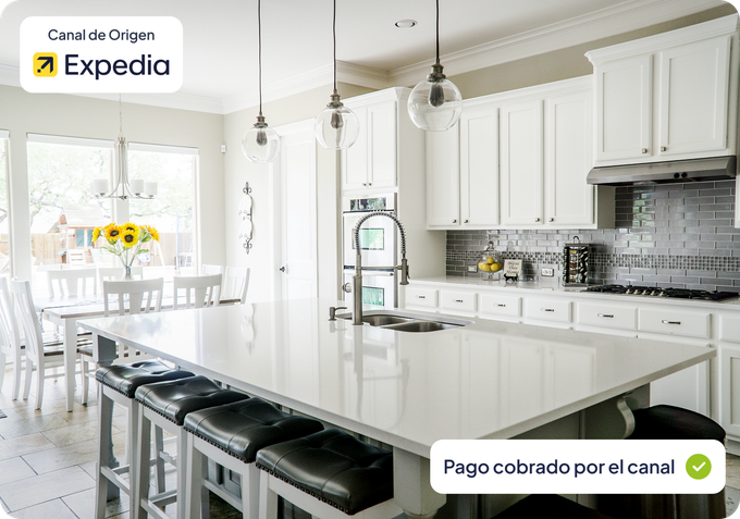 Cocina moderna de color blanco brillante con isla, taburetes negros y zona de comedor cerca de grandes ventanales.