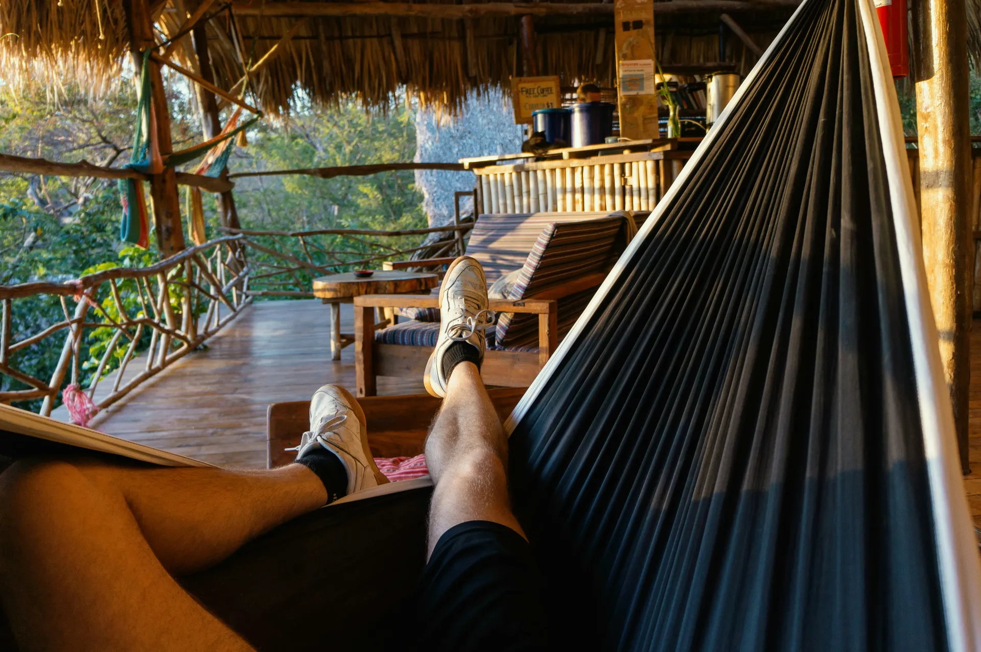 Relajándome en una hamaca negra en una terraza de madera con vistas a un río tropical y árboles.