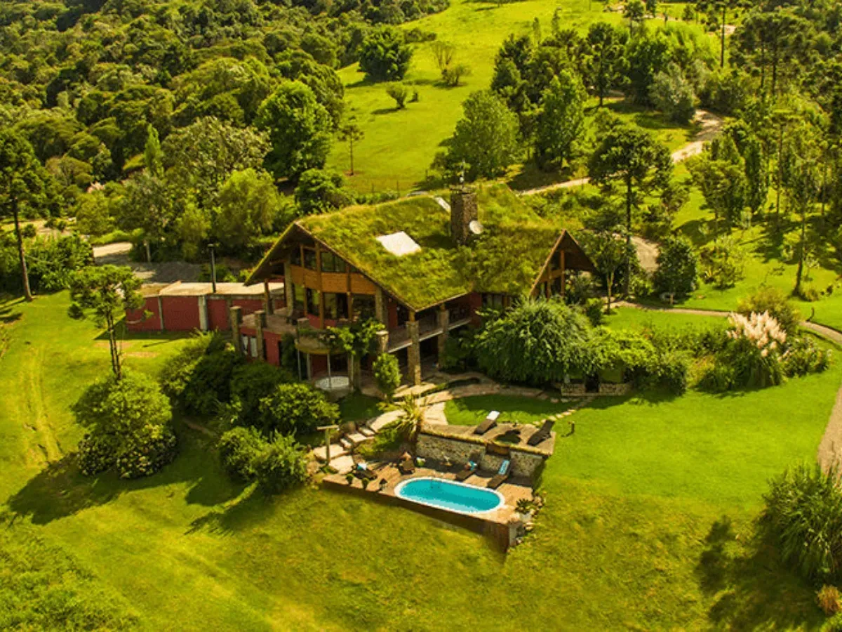 Un alojamiento tropical con piscina rodeado de exuberantes árboles y colinas verdes.