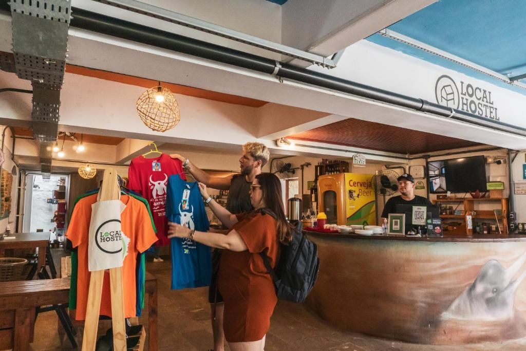 Clientes que miran camisetas de colores en un puesto de ropa dentro de un mercado.