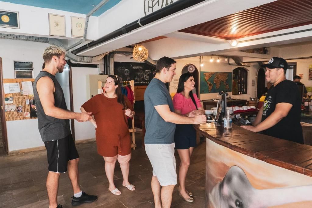 Gente charlando en un bar con bebidas, el camarero detrás de la barra, escena informal en un interior.