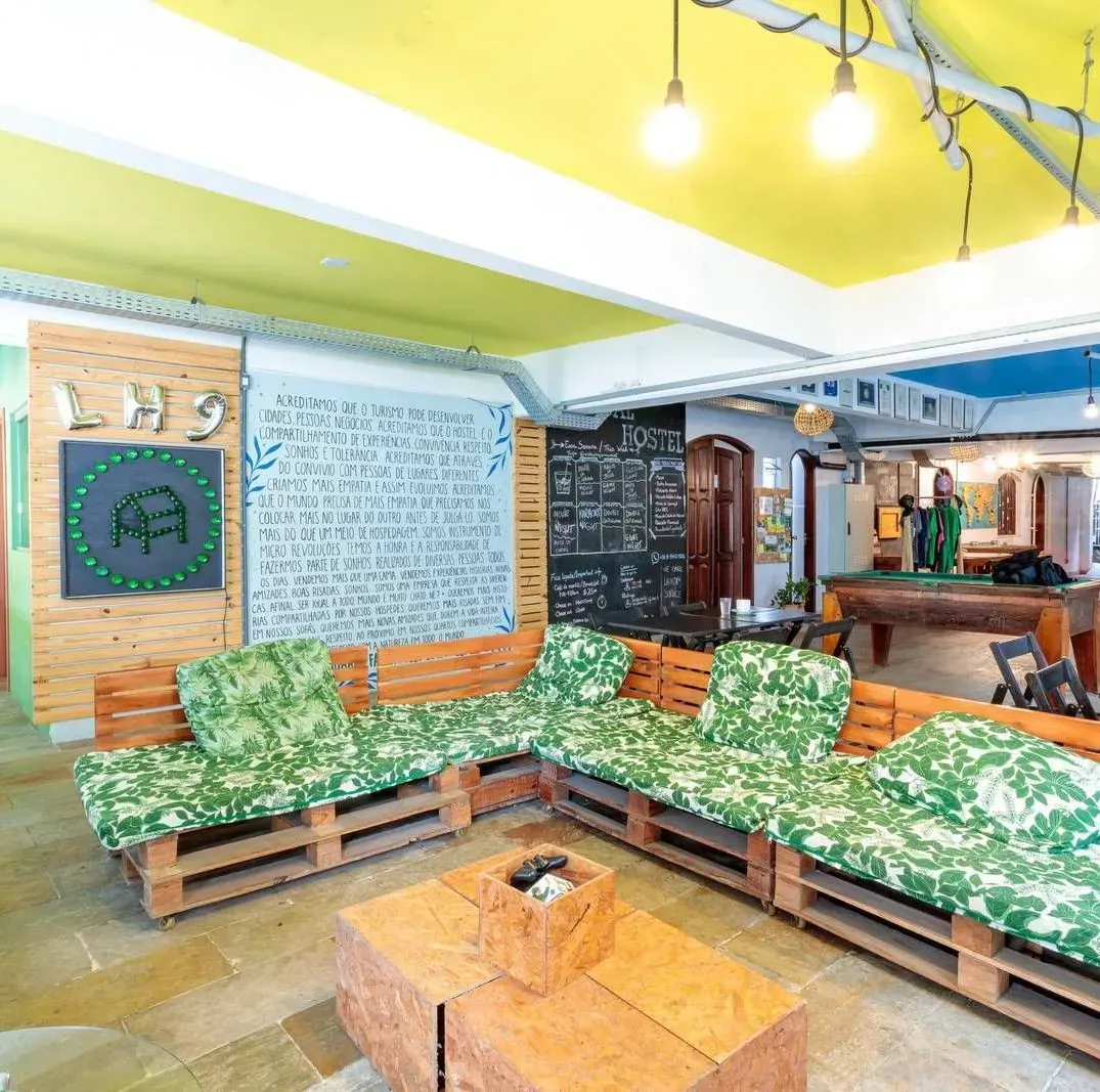 Salón luminoso con sofás de camuflaje verde, techo amarillo, pared de pizarra y mesa de centro de madera.