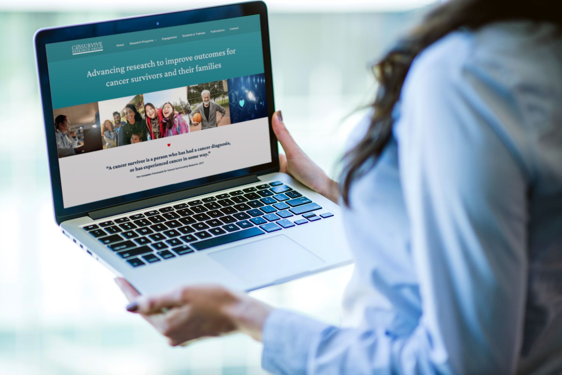 Woman holding laptop, viewing website with text and images.