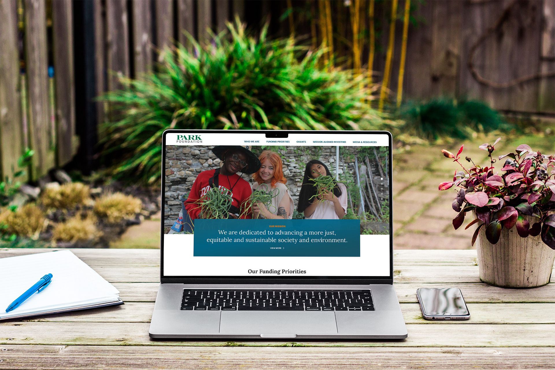 Laptop displaying website with people holding foliage, outdoors.