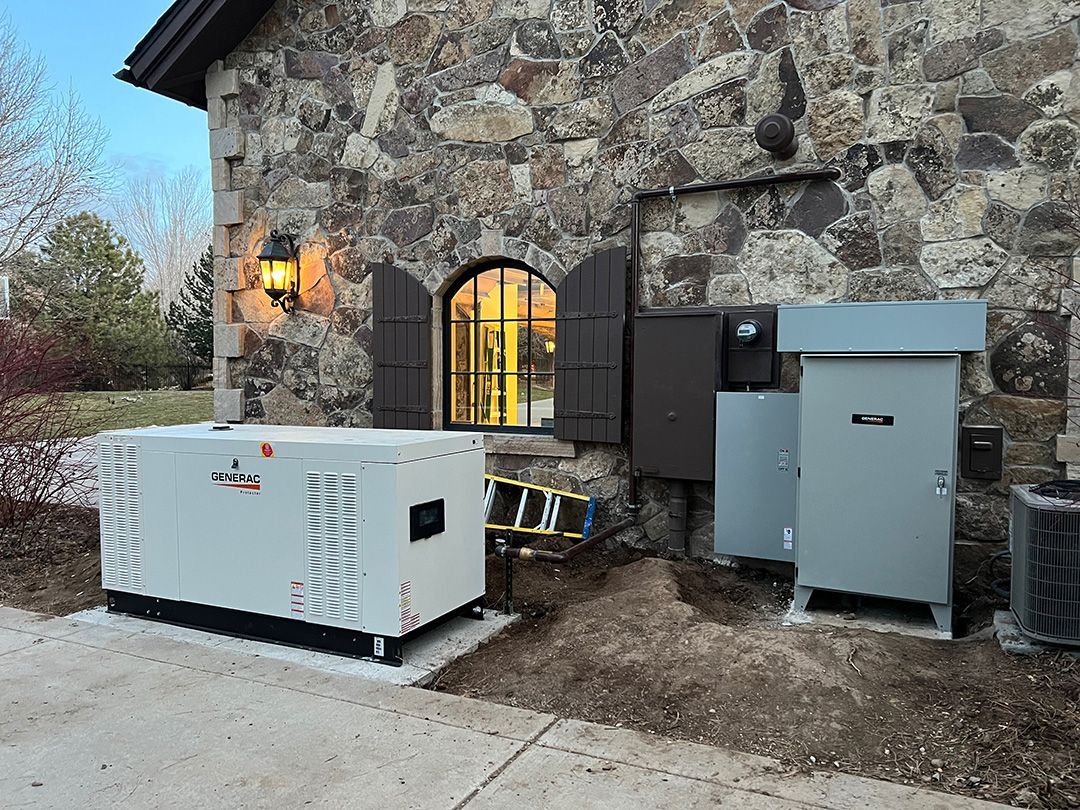 A generator and electrical boxes are mounted outside a stone building.