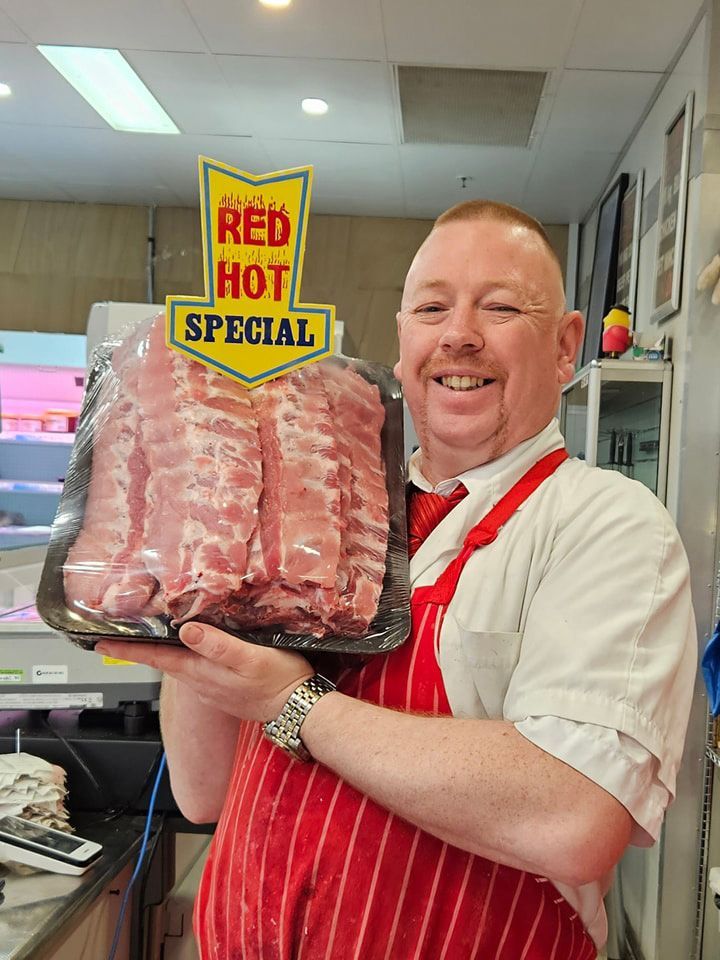 Man Is Holding A Tray Of Pork Ribs In A Butcher Shop — Elite Meats in Holt, ACT