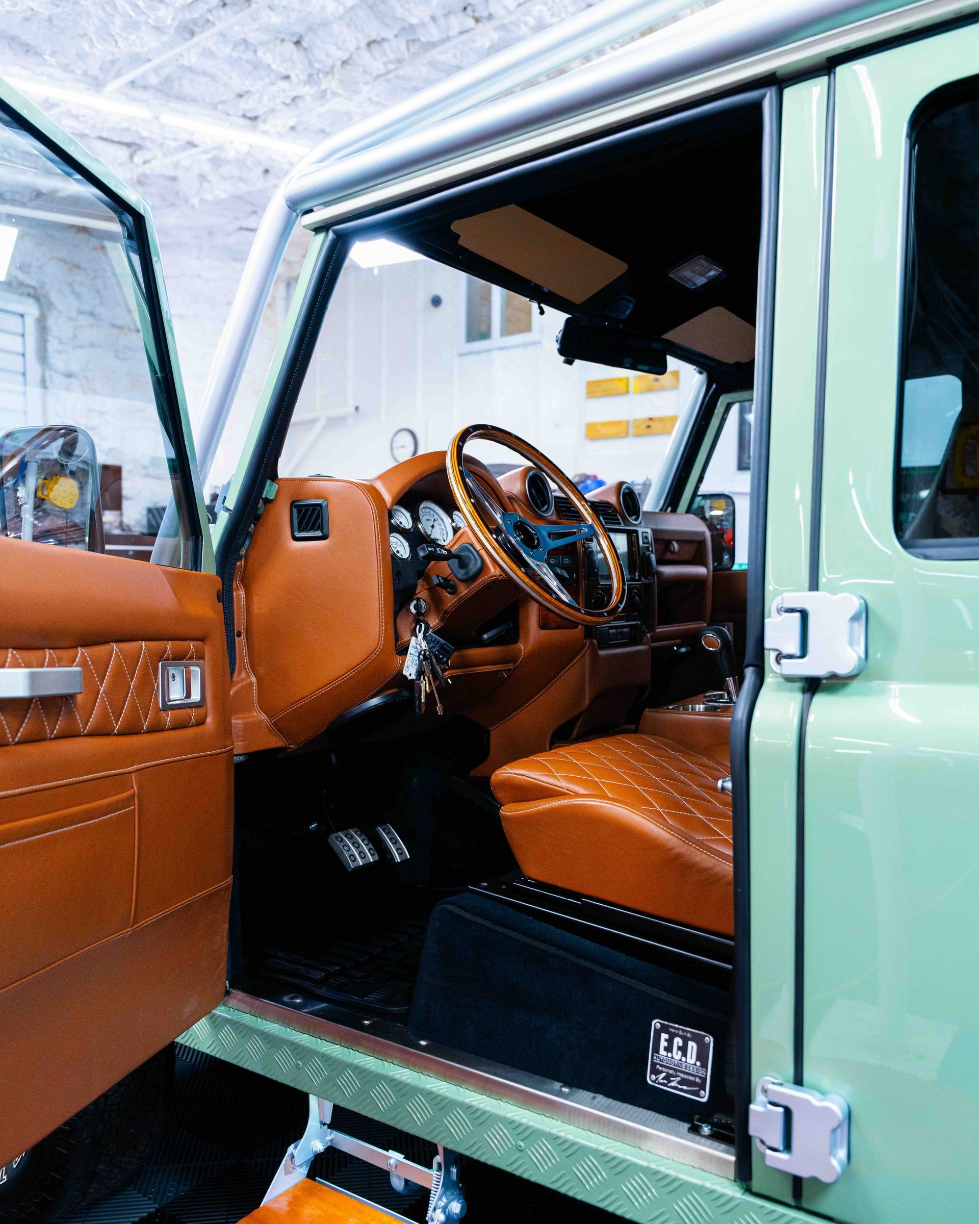 Open SUV door showing tan leather interior, steering wheel, and dashboard in a garage