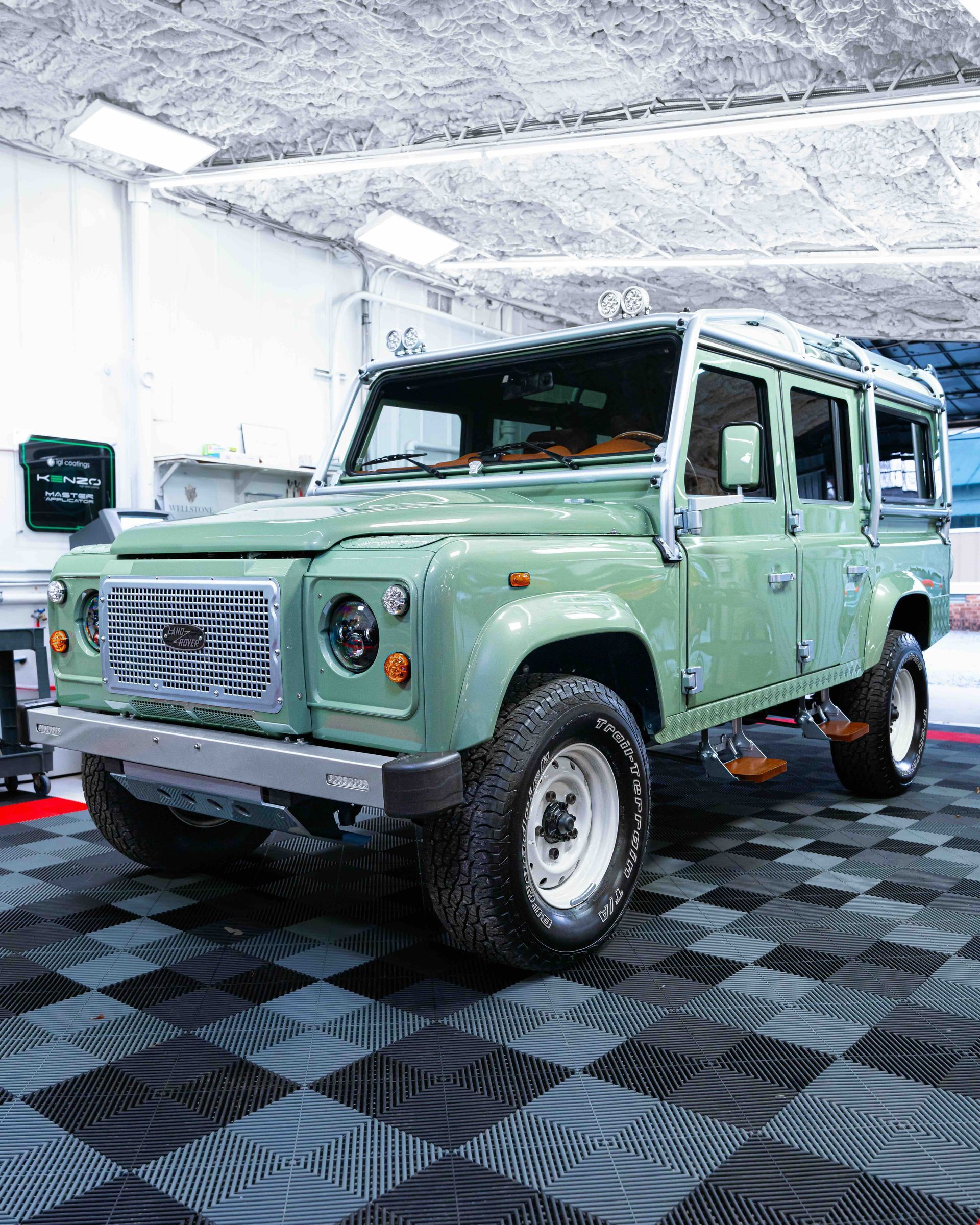 Mint green vintage Land Rover SUV displayed indoors on a checkered floor.