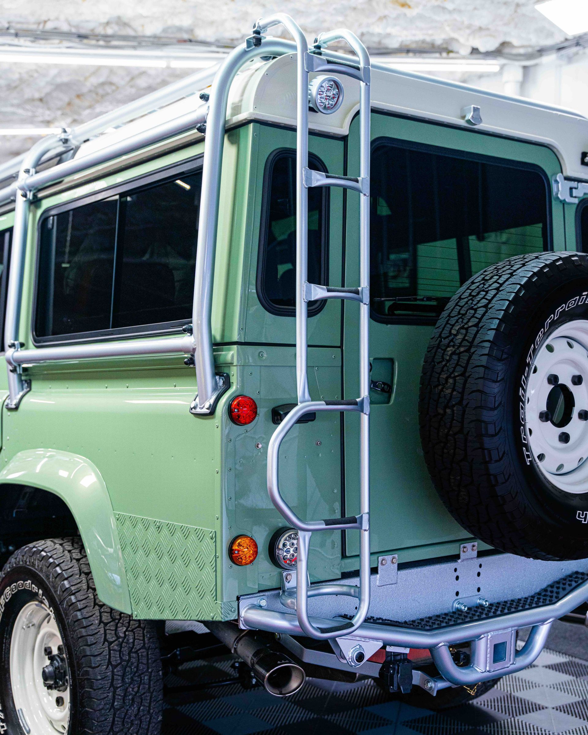 Mint-green off-road SUV with roof rack and rear spare tire, parked in snow