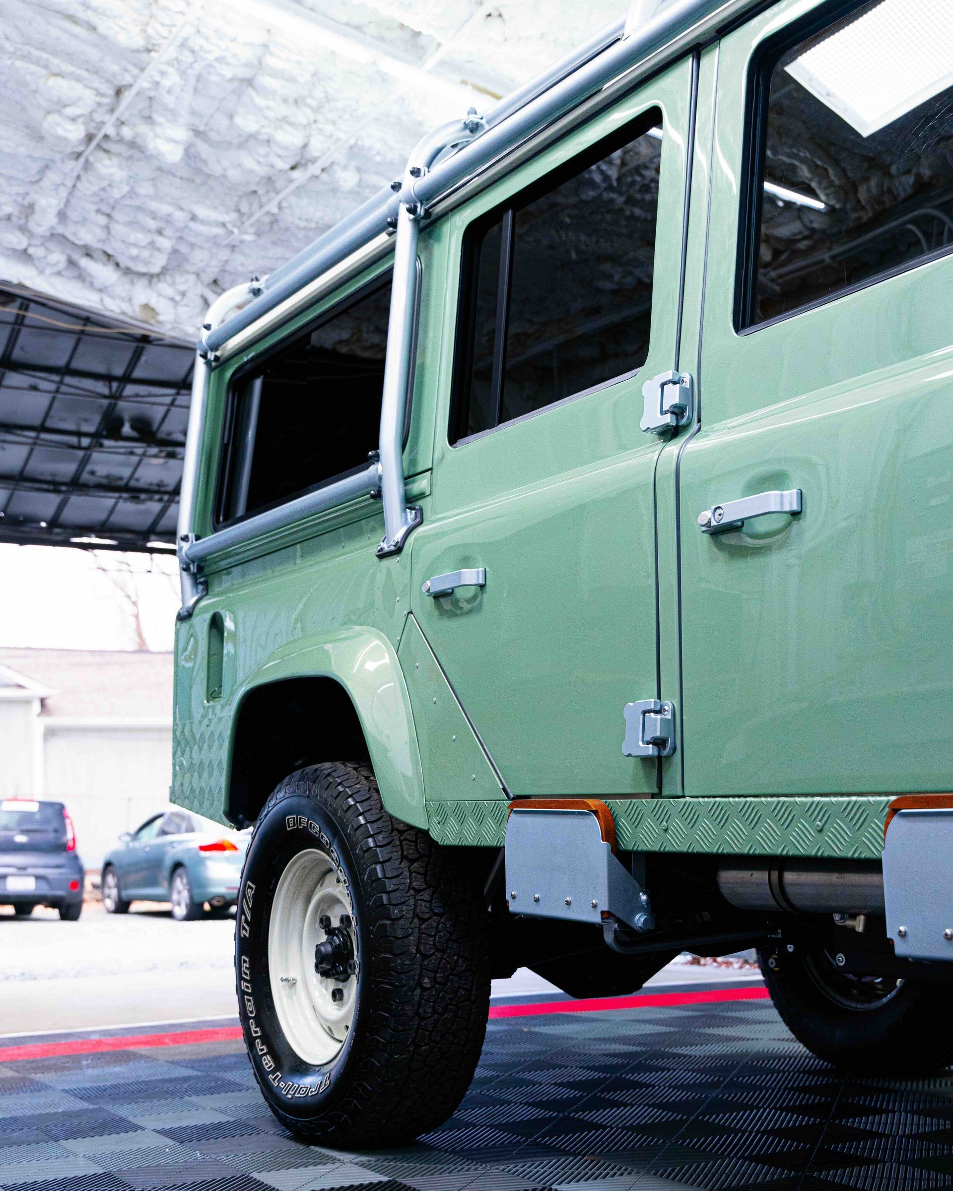 Mint-green vintage off-road SUV parked in a garage, rear side view, with large tires.
