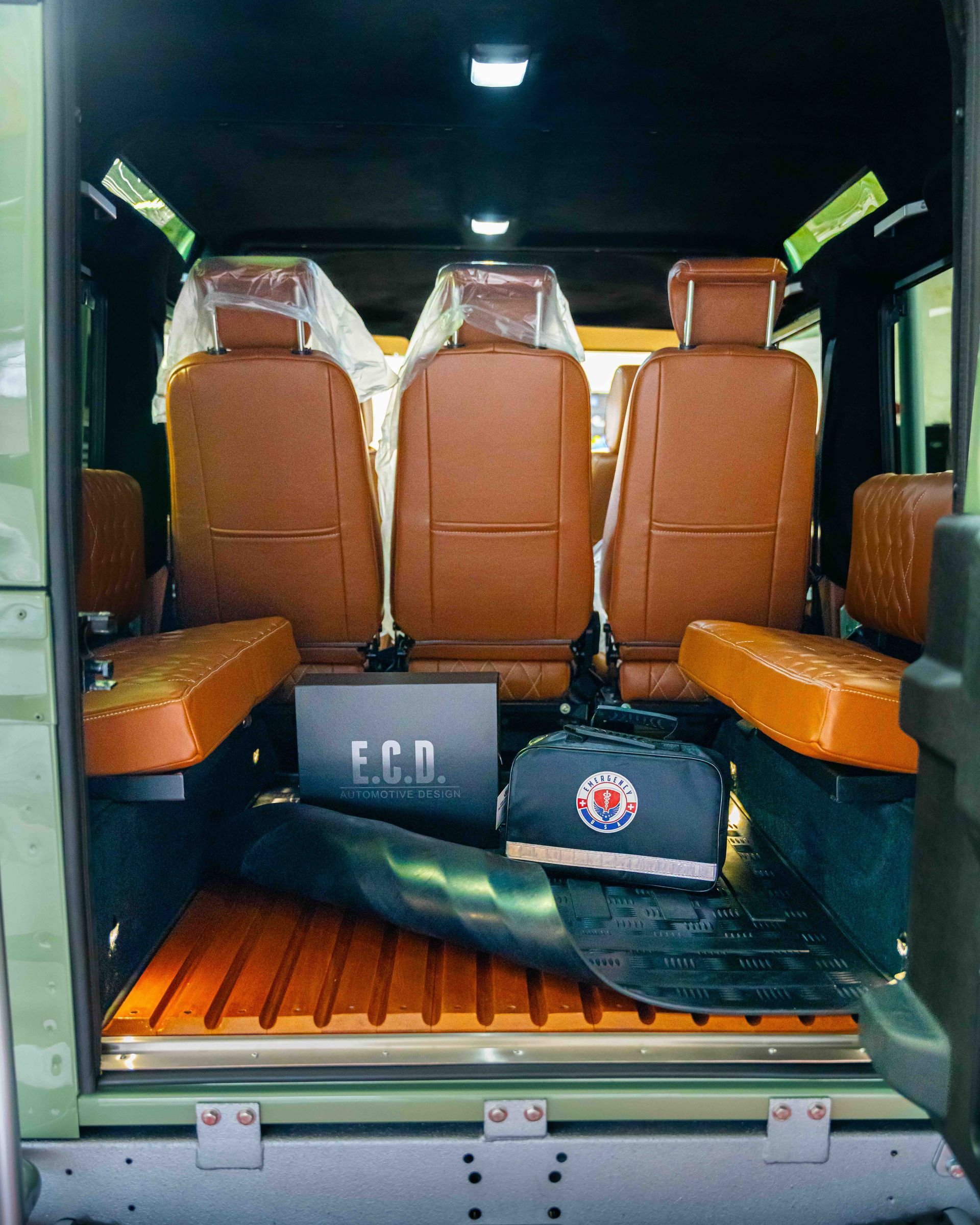Bus interior with brown seats and luggage on the floor, viewed from the rear doorway