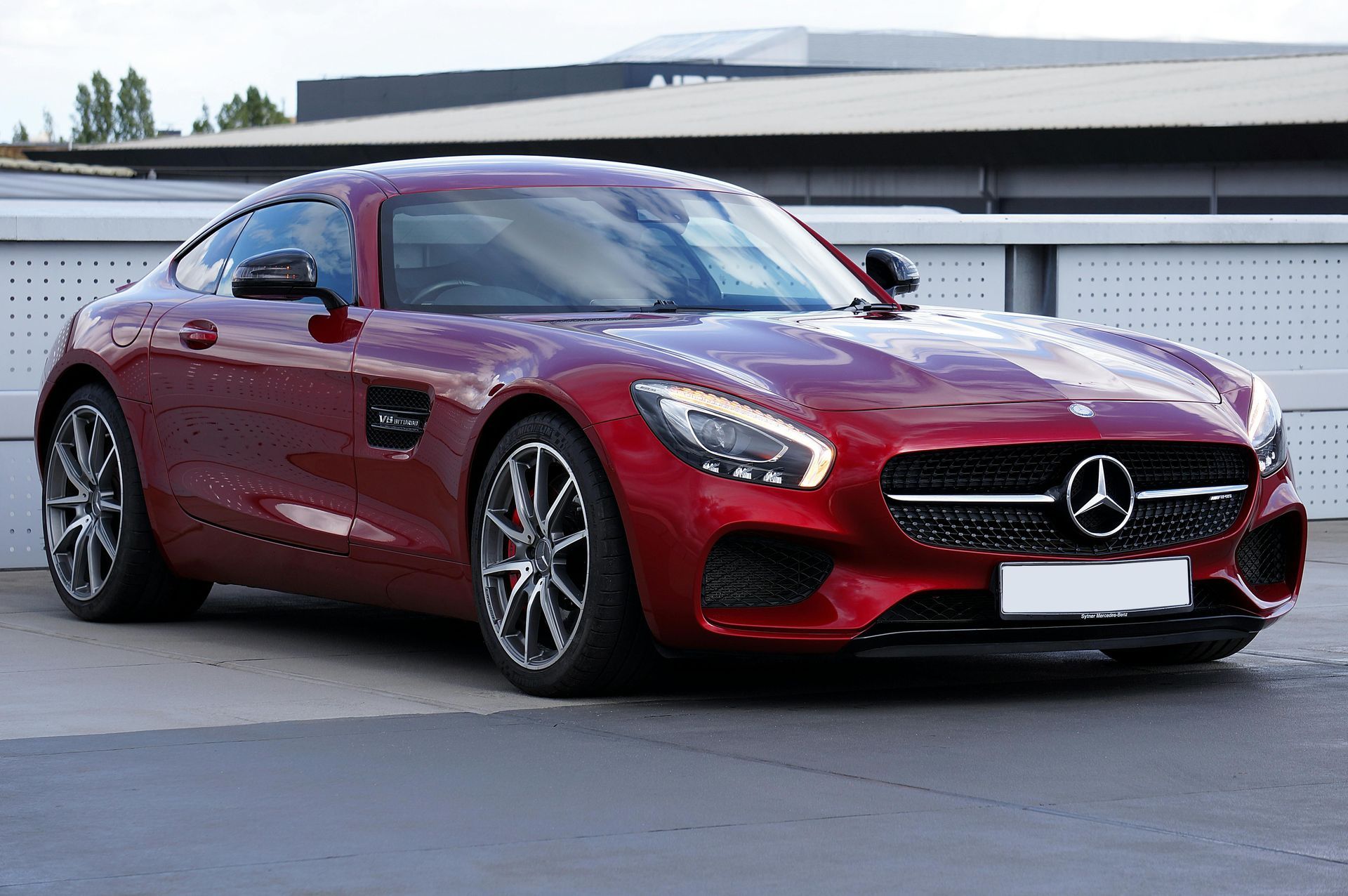 A red mercedes benz gt is parked in front of a building.