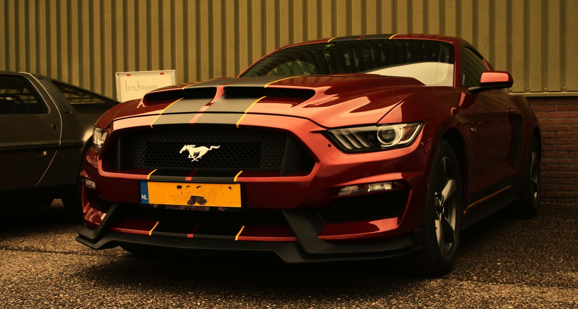 A red mustang is parked in front of a building.