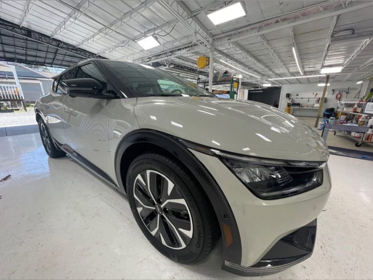 Silver crossover SUV parked inside a bright automotive detailing workshop.