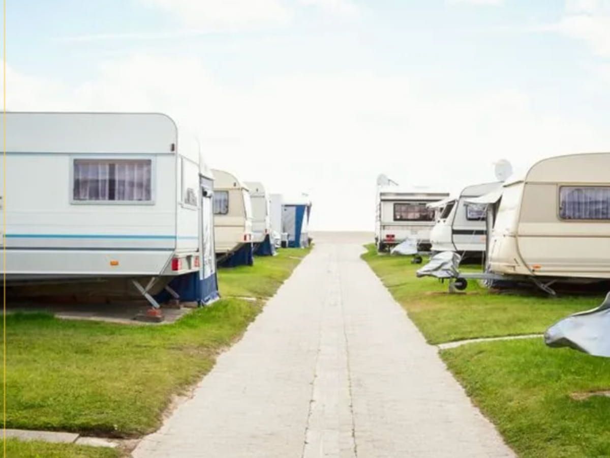 Travel trailers parked along an outdoor RV storage lane.