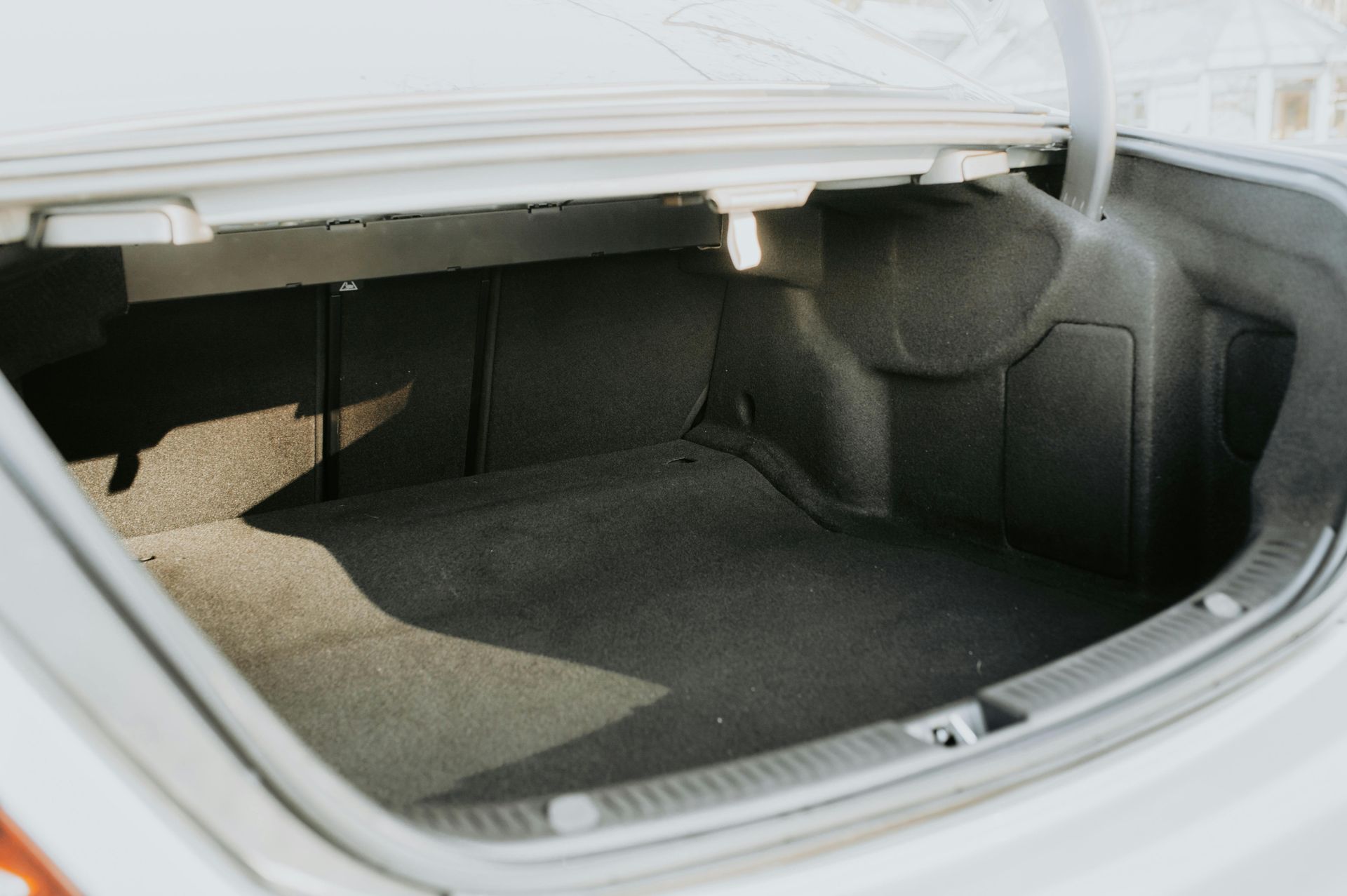 The trunk of a white car is open and empty.