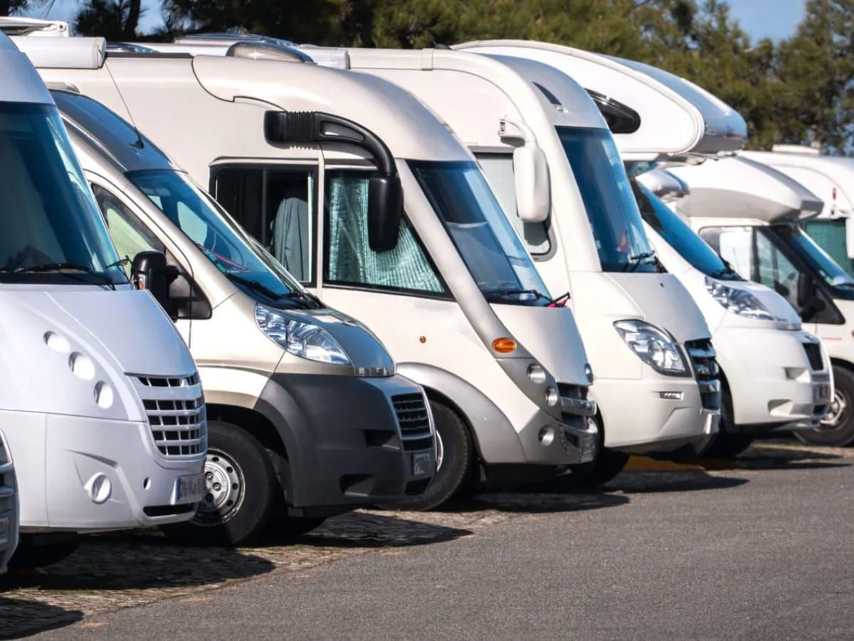 Row of motorhomes parked outdoors at an RV storage lot.