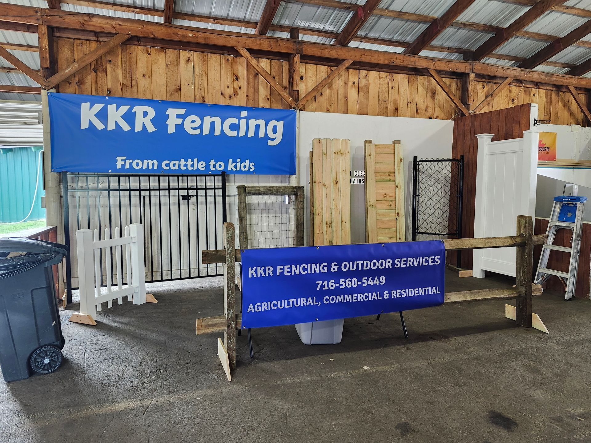 KKR Fencing booth with blue banners and display panels under a wooden tent at an outdoor market