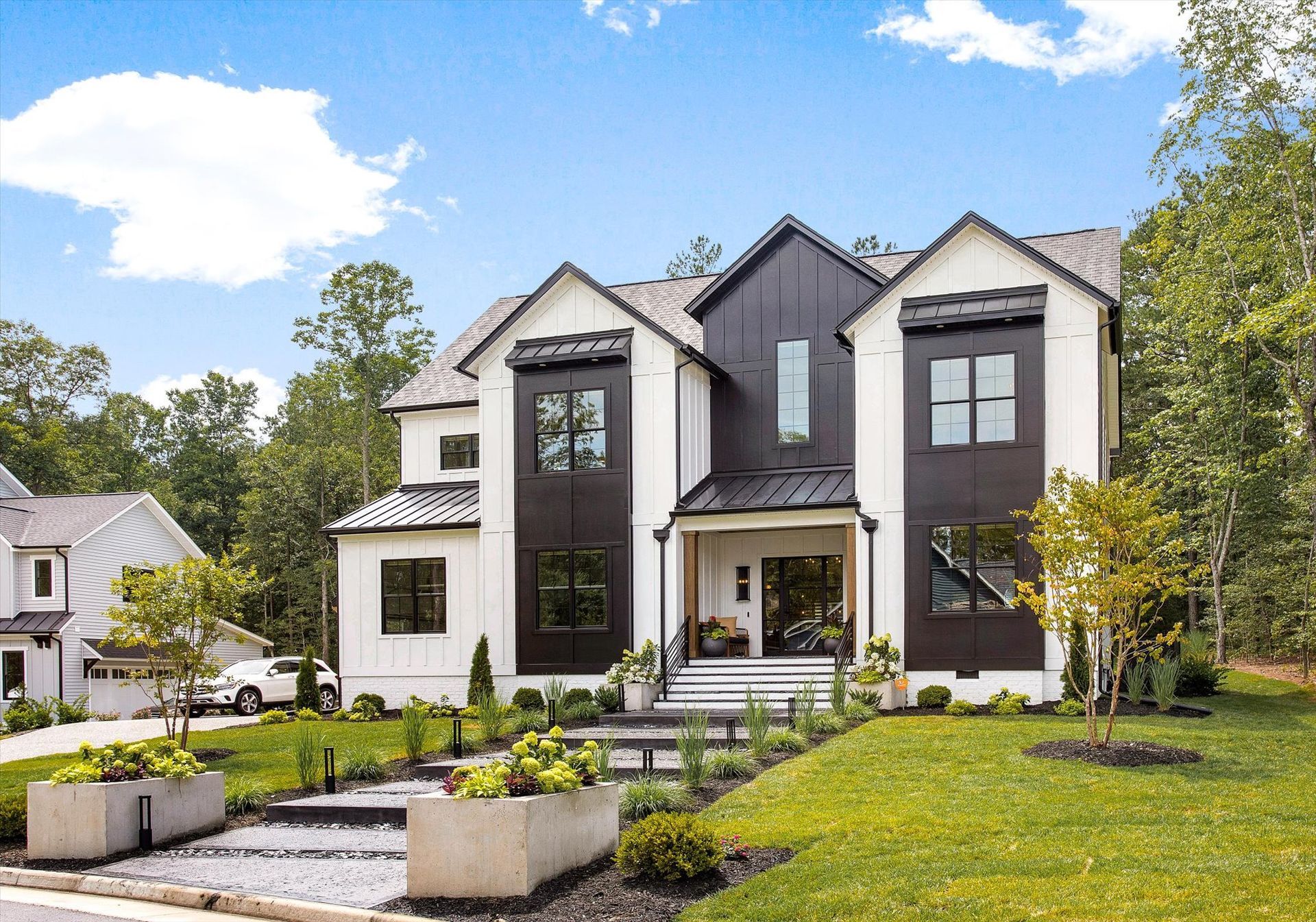A large black and white house with a lot of windows is sitting on top of a lush green lawn.