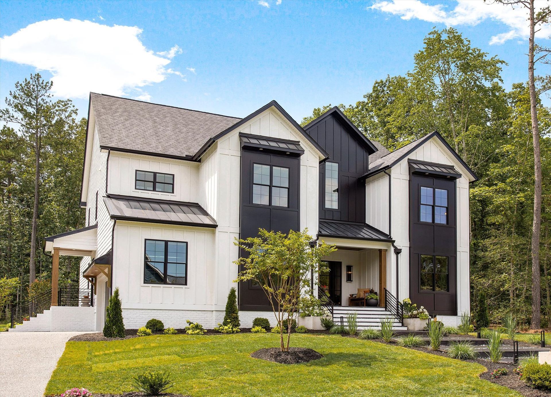 A large white and black house with a lot of windows and trees in the background.