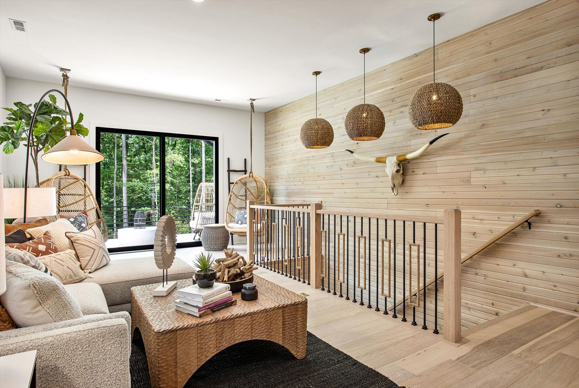 A living room with a couch , chair , coffee table and stairs.