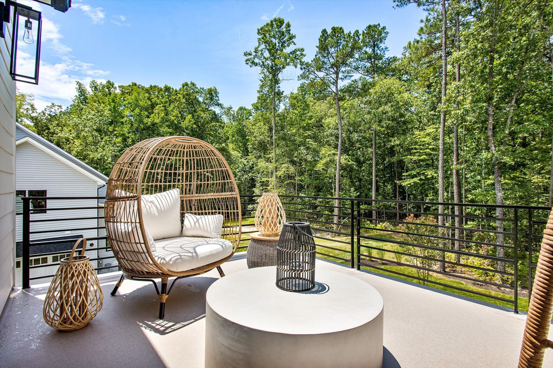 A balcony with a wicker chair , table , and lanterns.