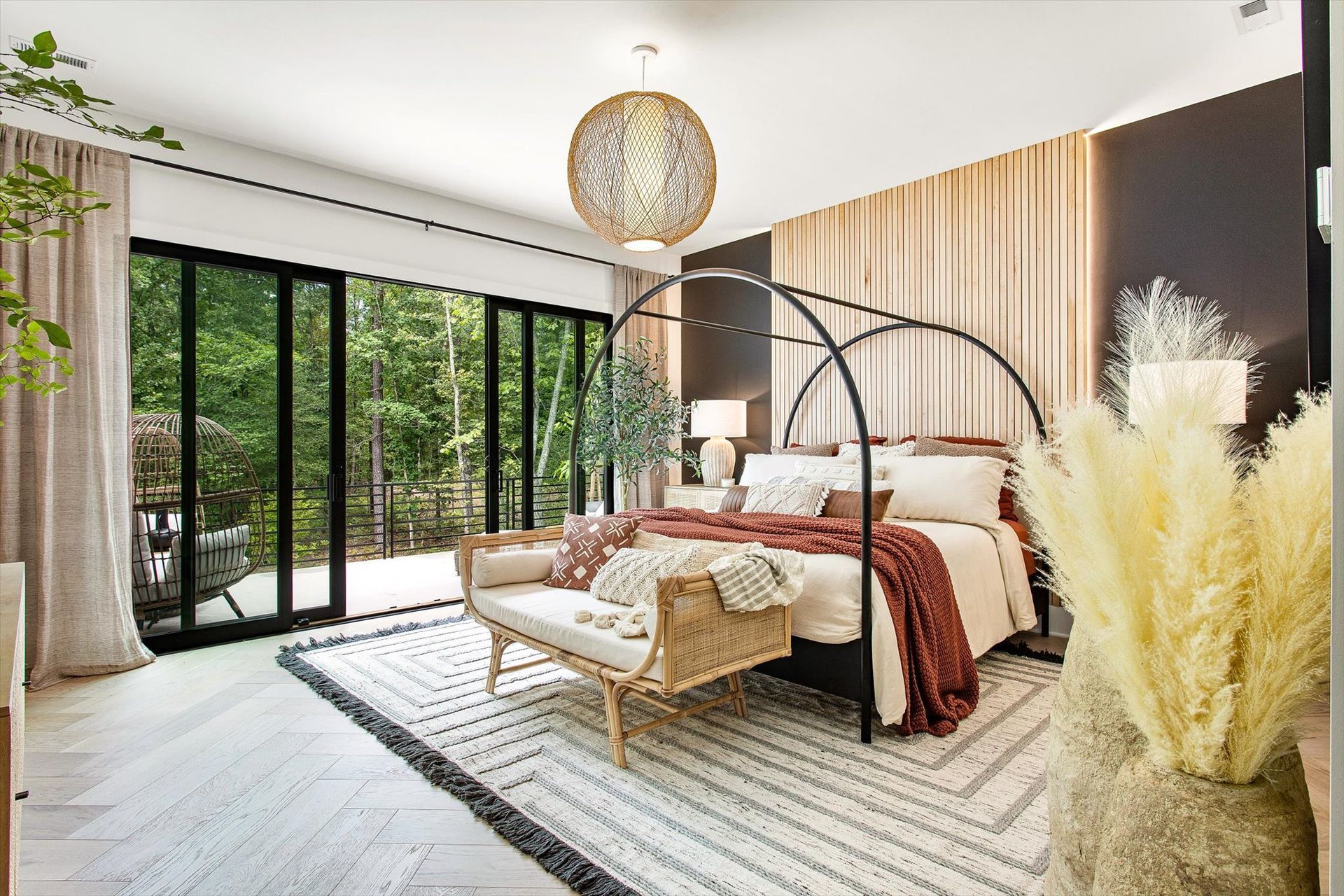 A bedroom with a canopy bed , bench , rug and sliding glass doors.