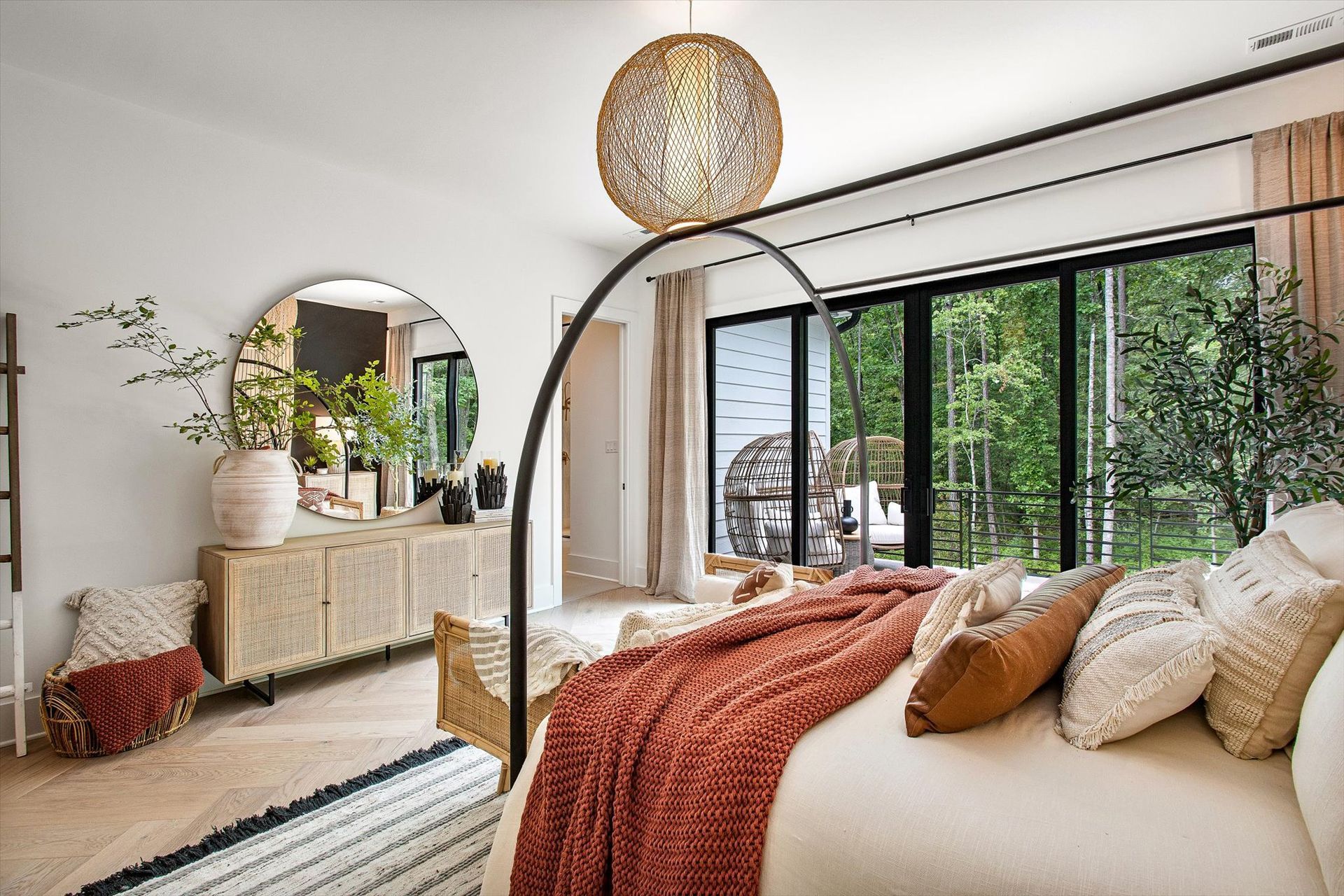 A bedroom with a canopy bed , dresser , mirror and lots of windows.
