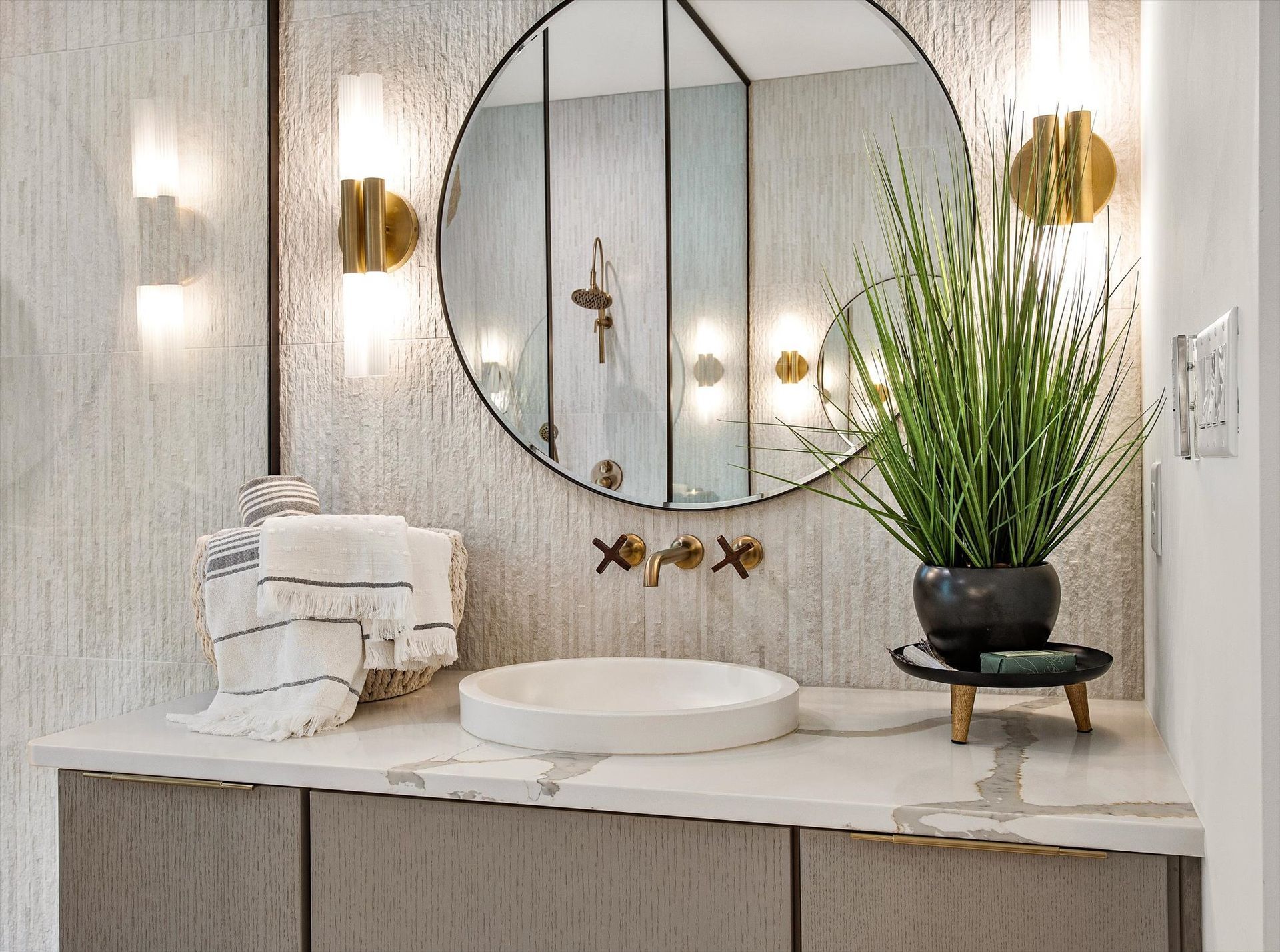 A bathroom with a sink and a round mirror.
