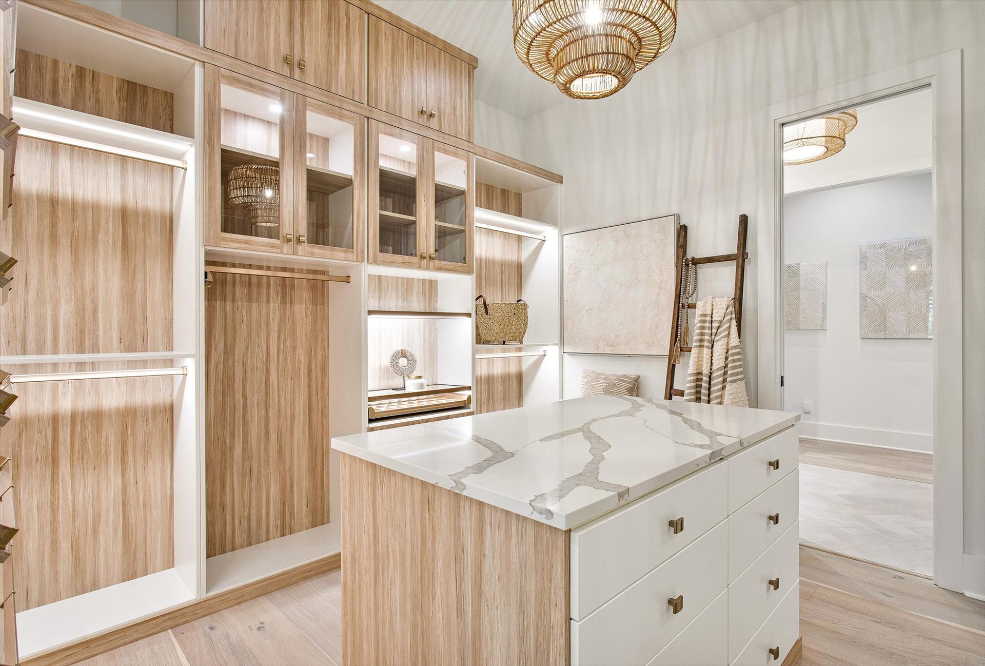 A walk in closet with wooden cabinets and a large island in the middle.