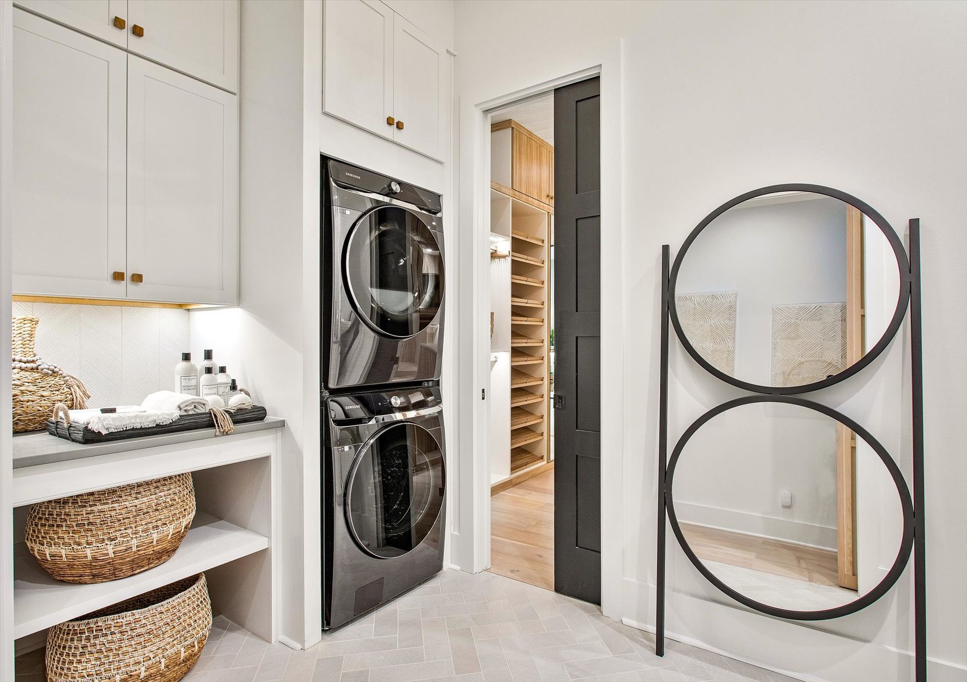 A laundry room with a washer and dryer stacked on top of each other and a mirror.