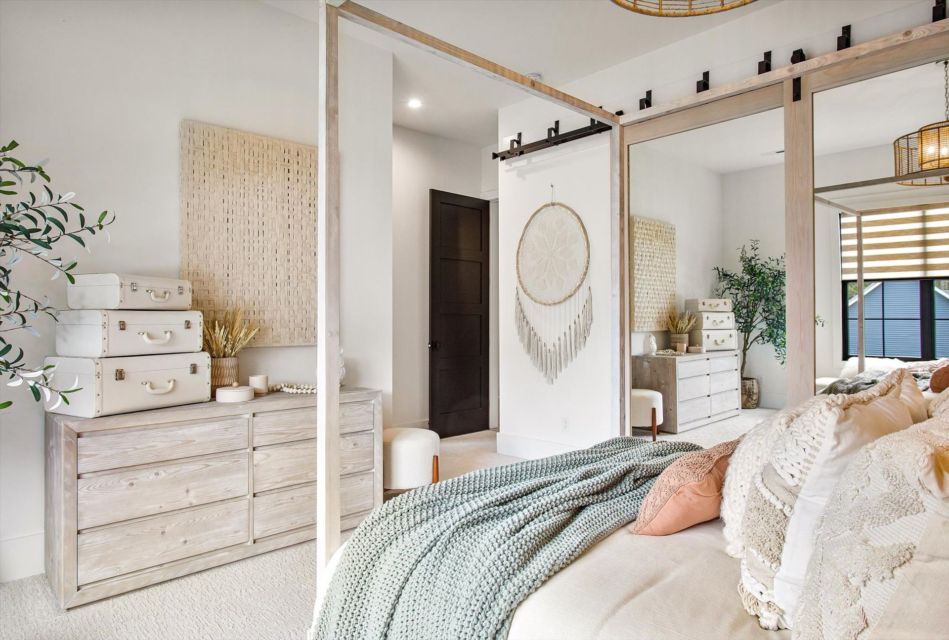 A bedroom with a canopy bed , dresser , and mirrors.
