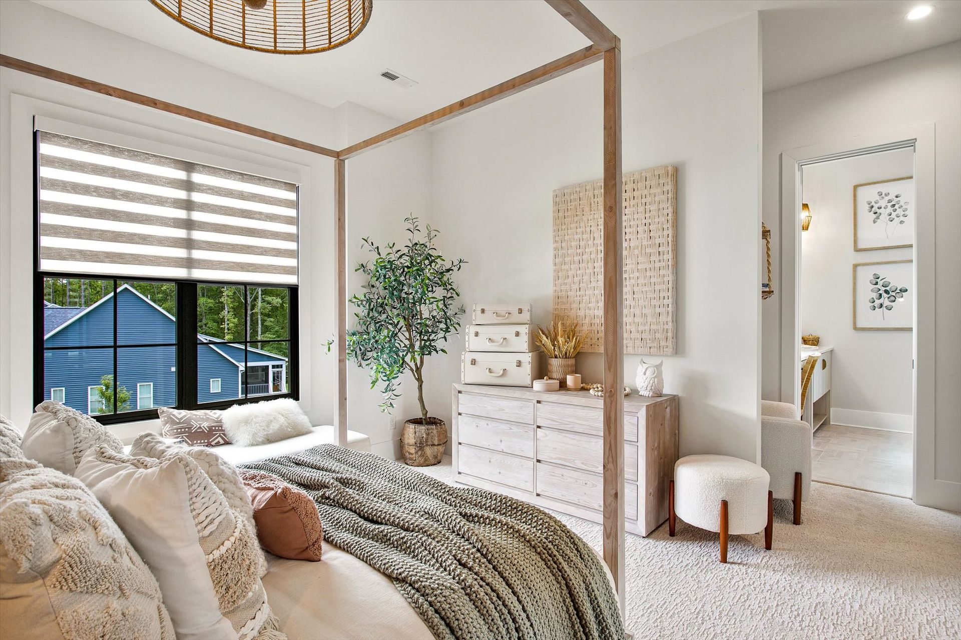 A bedroom with a canopy bed , dresser , chair and window.