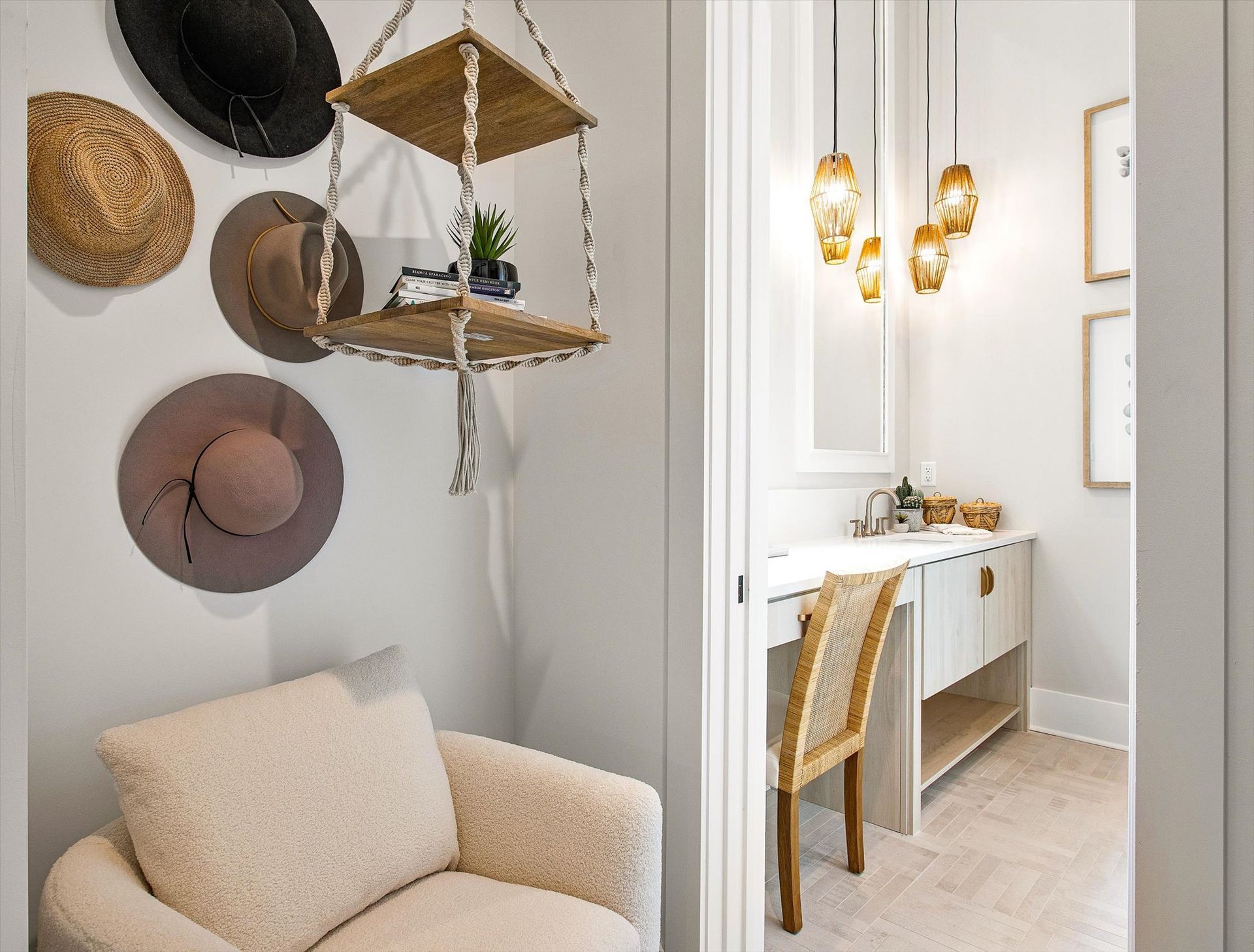 A room with a chair and a shelf with hats hanging on the wall.