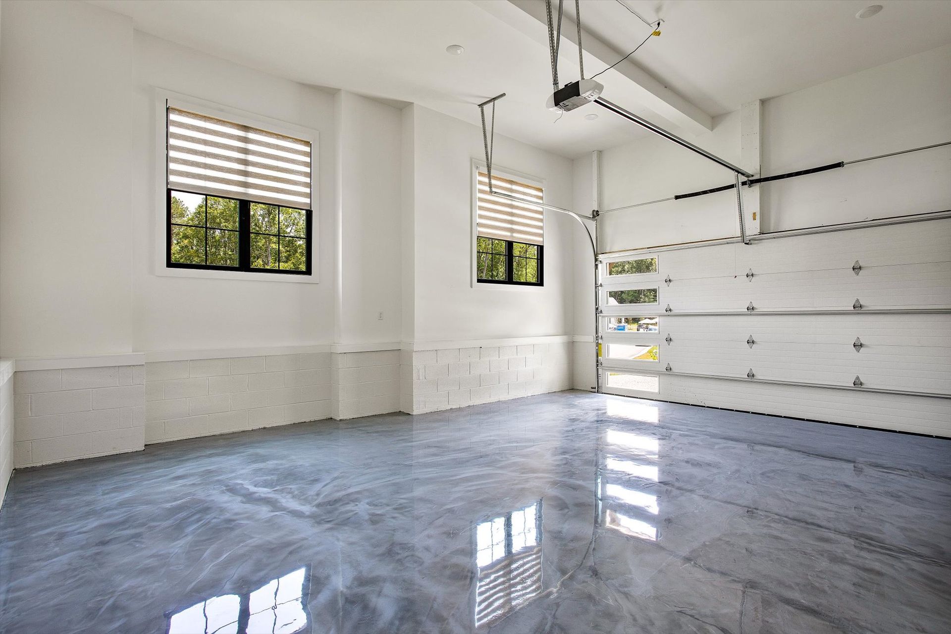 An empty garage with a garage door open and a window.