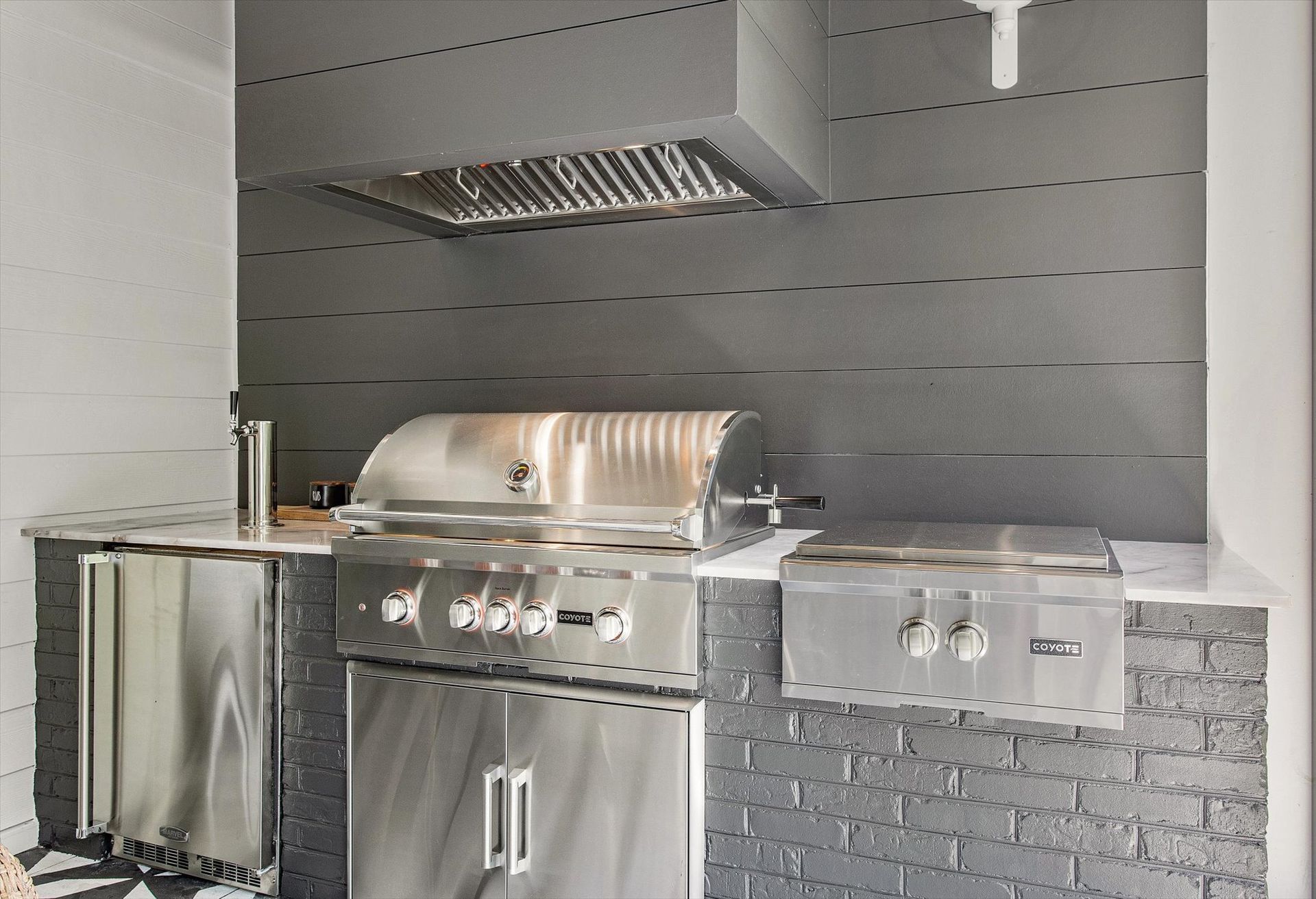 A stainless steel grill is mounted to the wall in a kitchen.