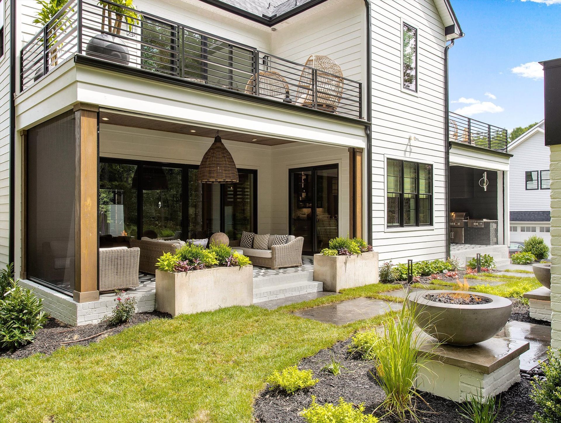 A large white house with a patio and a fire pit in the backyard.
