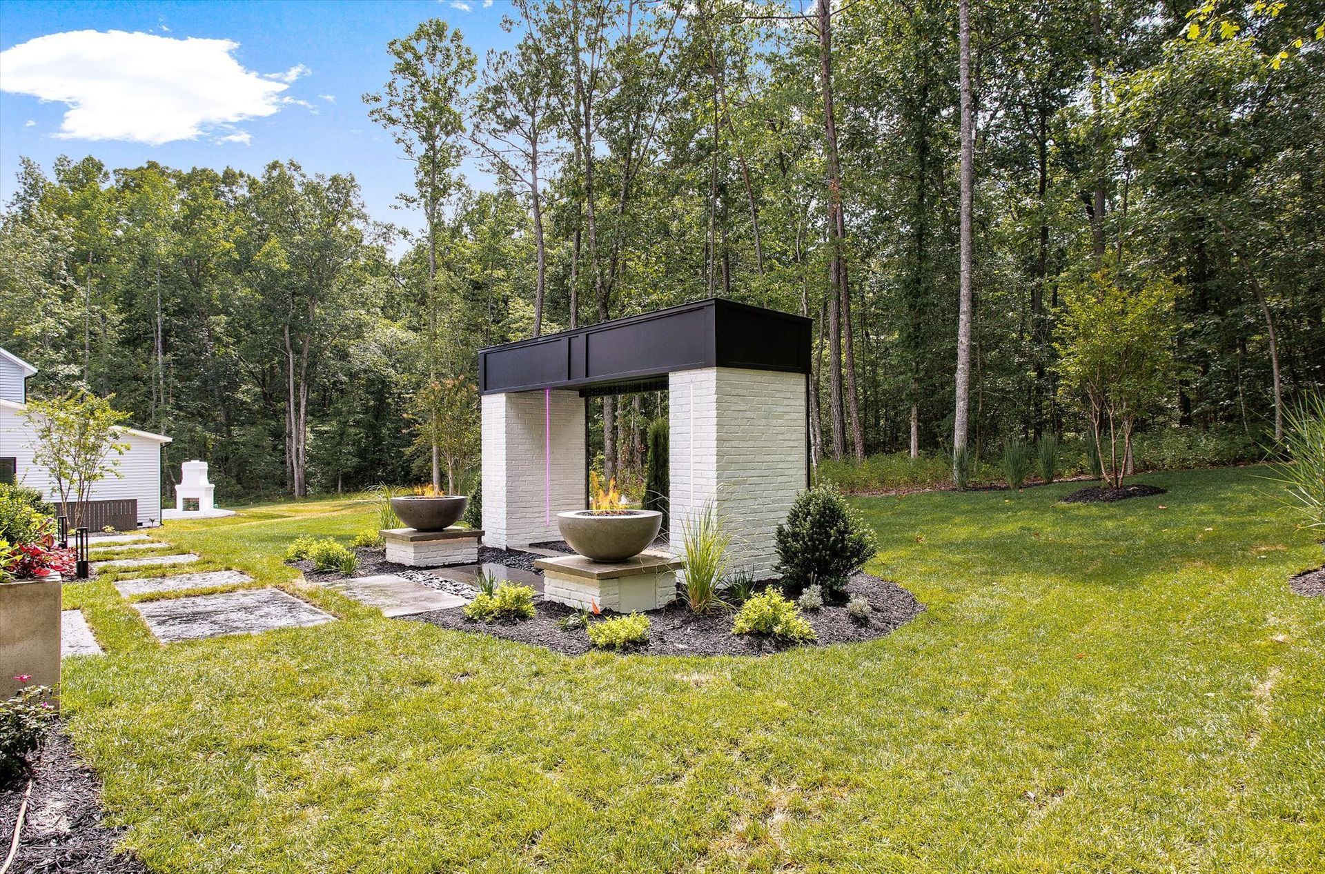 There is a fireplace in the middle of a lush green field surrounded by trees.